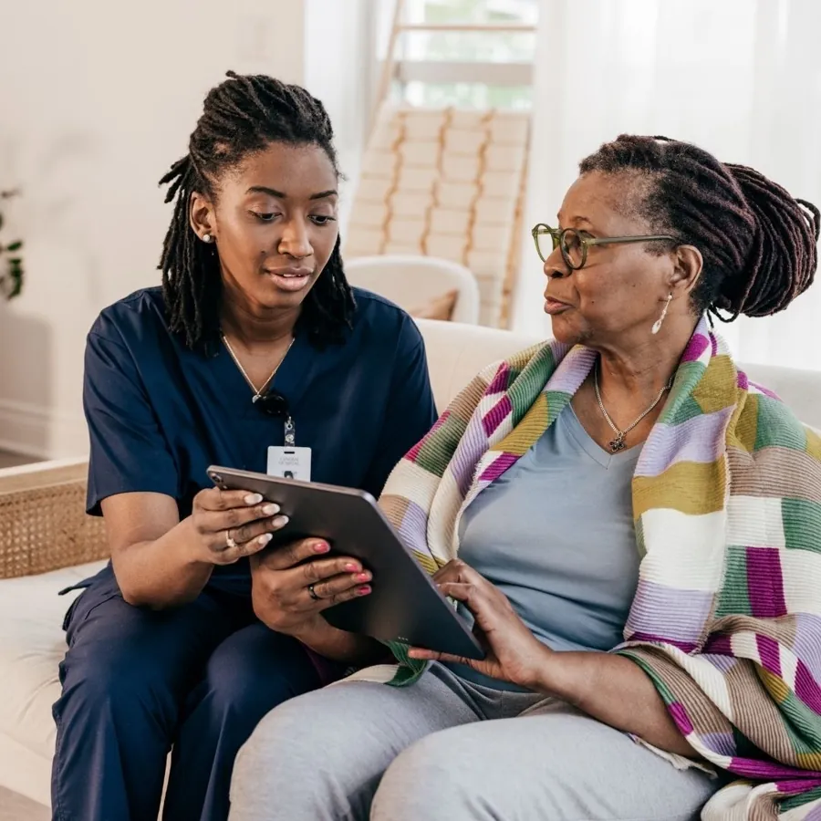 A carer showing an older woman a tablet at home