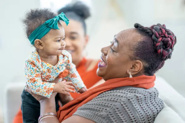 A grandmother, a mother and her baby laughing together at home